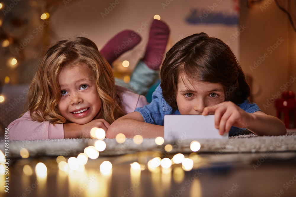 Fotografie Focus on smiling enthusiastic kids using modern smartphone