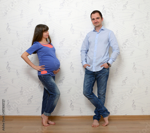 Young pregnant woman and man standing at home