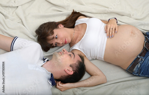 Content pregnant couple posing on bed