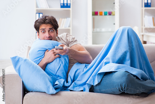 Man watching tv from bed holding remote control unit
