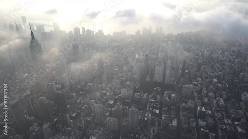 New York City aerial view flying over the Flatiron District in Manhattan, facing the East River, with low level clouds and thick fog at sunrise.