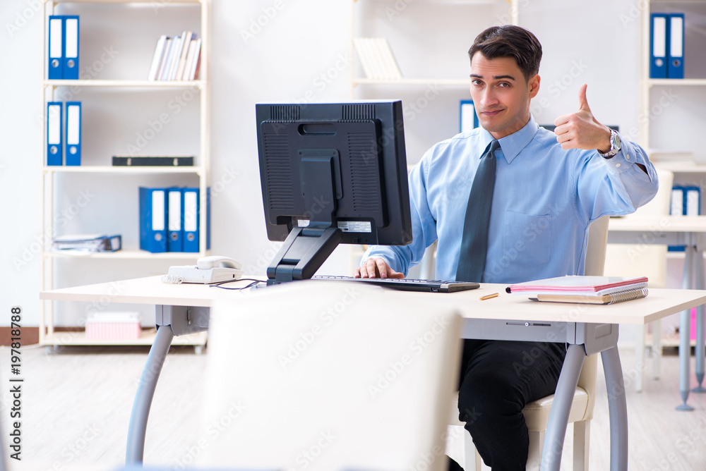 Handsome businessman employee sitting at his desk in office Handsome businessman employee sitting at his desk in office