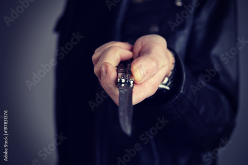 Canvas Print man in black leather jacket showing butterfly knife