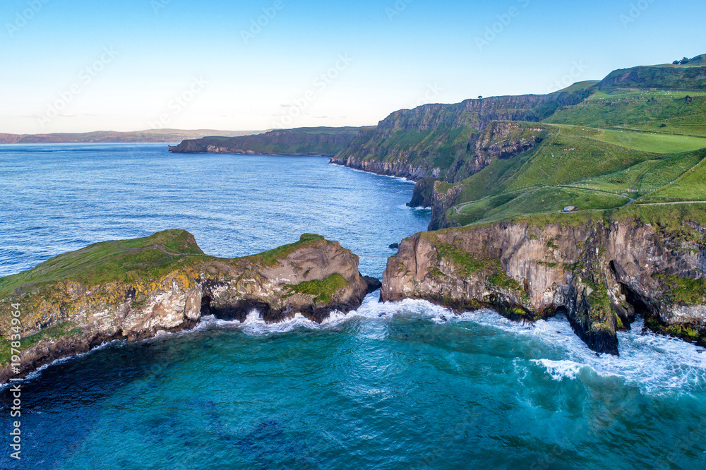 Northern Ireland, UK. Atlantic coast with cliffs and far aerial view of Carrick-a-Rede Rope Bridge in County Antrim