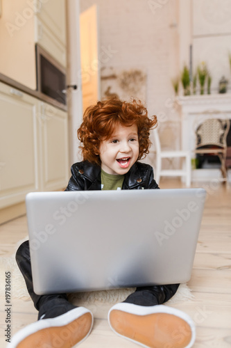 Little redhead boy uses a laptop