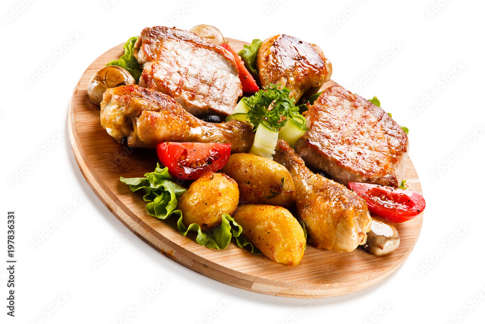 Grilled steak and drumsticks with potatoes on cutting board