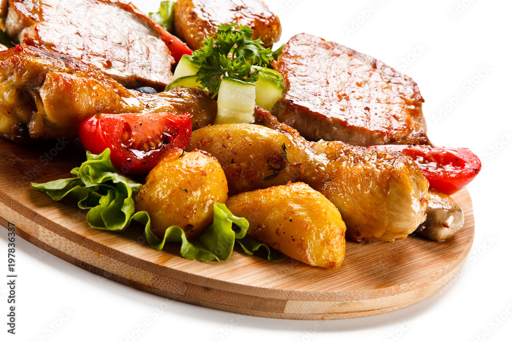 Grilled steak and drumsticks with potatoes on cutting board Grilled steak and drumsticks with potatoes on cutting board