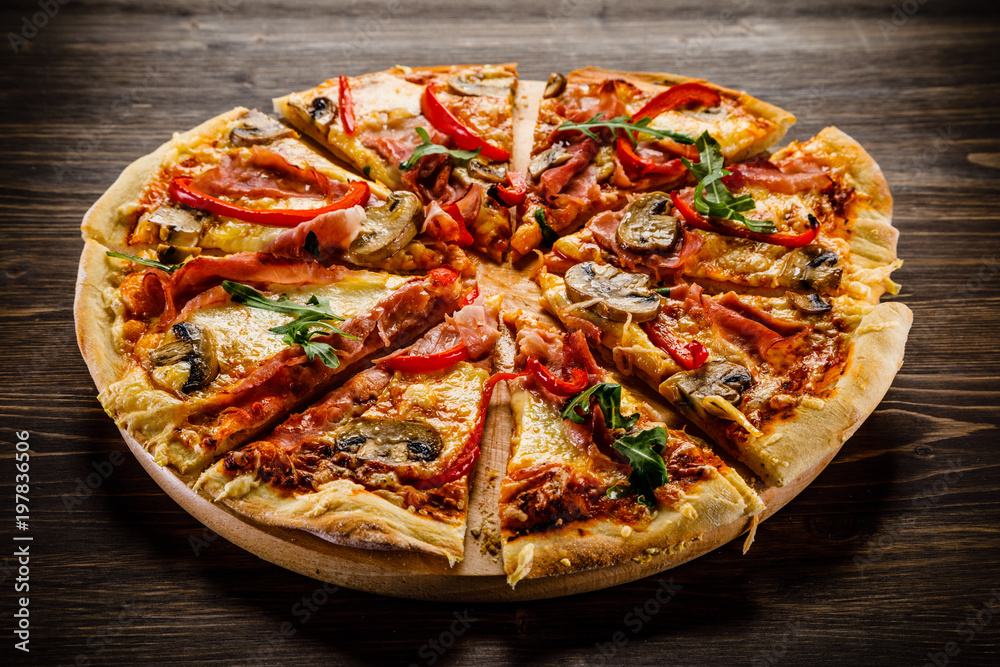 Pizza with ham and vegetables on wooden table Pizza with ham and vegetables on wooden table