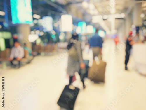 Abstract blurred image background of group people or arriving passengers with their suitcases holding luggage walking in international airport terminal, travelling or business concept. vintage tone.