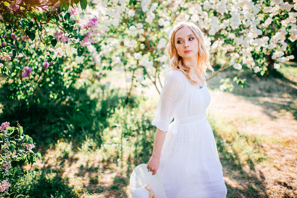 Fine art portrait of young blonde girl in white elegant dress in summer blooming lilac garden. Colorful bushes with flowers on branches. Beautiful cinderella fahion style. Pretty woman at nature. Fine art portrait of young blonde girl in white elegant dress in summer blooming lilac garden. Colorful bushes with flowers on branches. Beautiful cinderella fahion style. Pretty woman at nature.