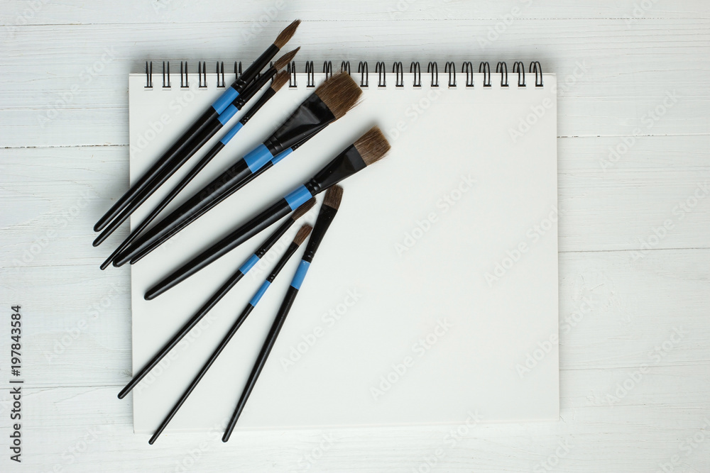 Paint brushes and empty sketchbook Paint brushes and empty sketchbook