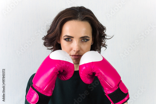 beautiful young woman black curly hair with pink boxing gloves looking at tge camera photo