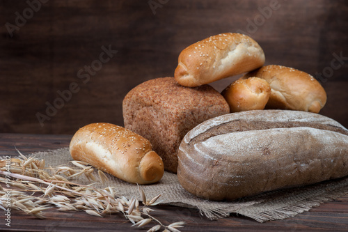 Bread with ear and textured fabric on wooden background photo