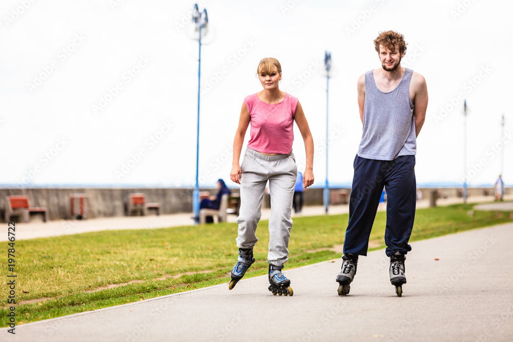 Friends rollerblading together have fun in park.