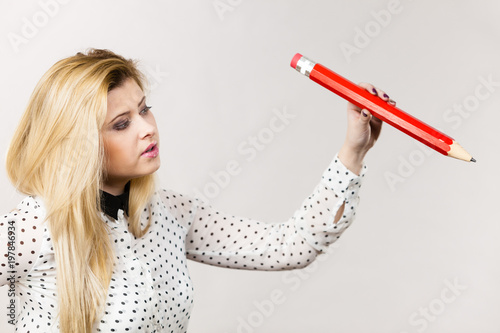 Positive woman holds big pencil in hand