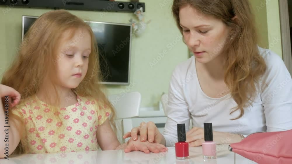Mother and daughter having fun painting fingernails, family time concept