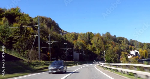 Road 8, C4k driving view through  a on highway 8, and countryside nature, finaly revealing the turquoise thunersee lake, in berner oberland, on a sunny autumn day, in the swiss alps of Switzerland photo