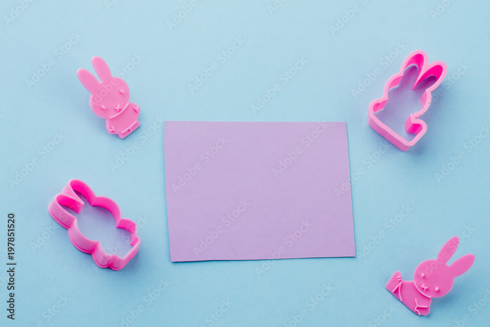Set of rabbit shaped silicone molds. Silicone cake molds and blank paper card on blue background, top view. Set of rabbit shaped silicone molds. Silicone cake molds and blank paper card on blue background, top view.