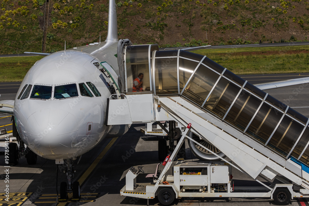 Obraz premium Plane with passenger boarding bridge connected to the door at the airport allowing passengers to board and disembark without going outside or being exposed to the elements