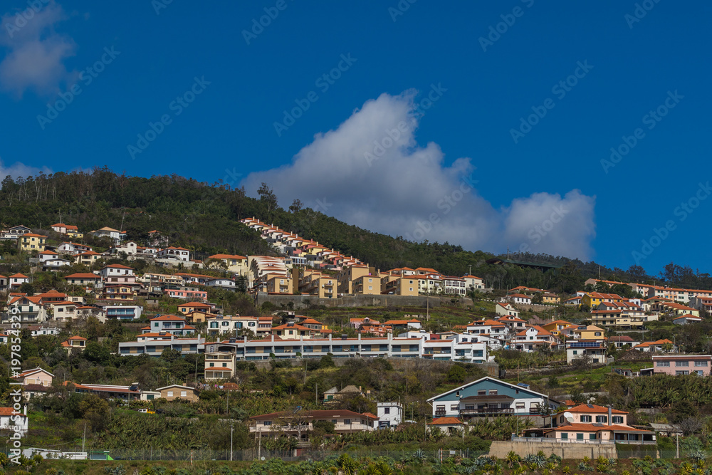 Lanscape with colorful houses on the hills under the dramatic cloudy sky on a sunny day