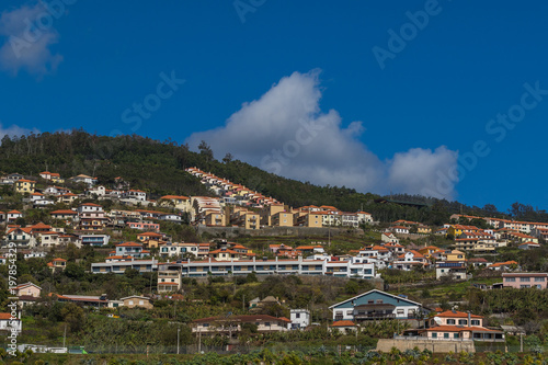 Fototapeta Naklejka Na Ścianę i Meble -  Lanscape with colorful houses on the hills under the dramatic cloudy sky on a sunny day