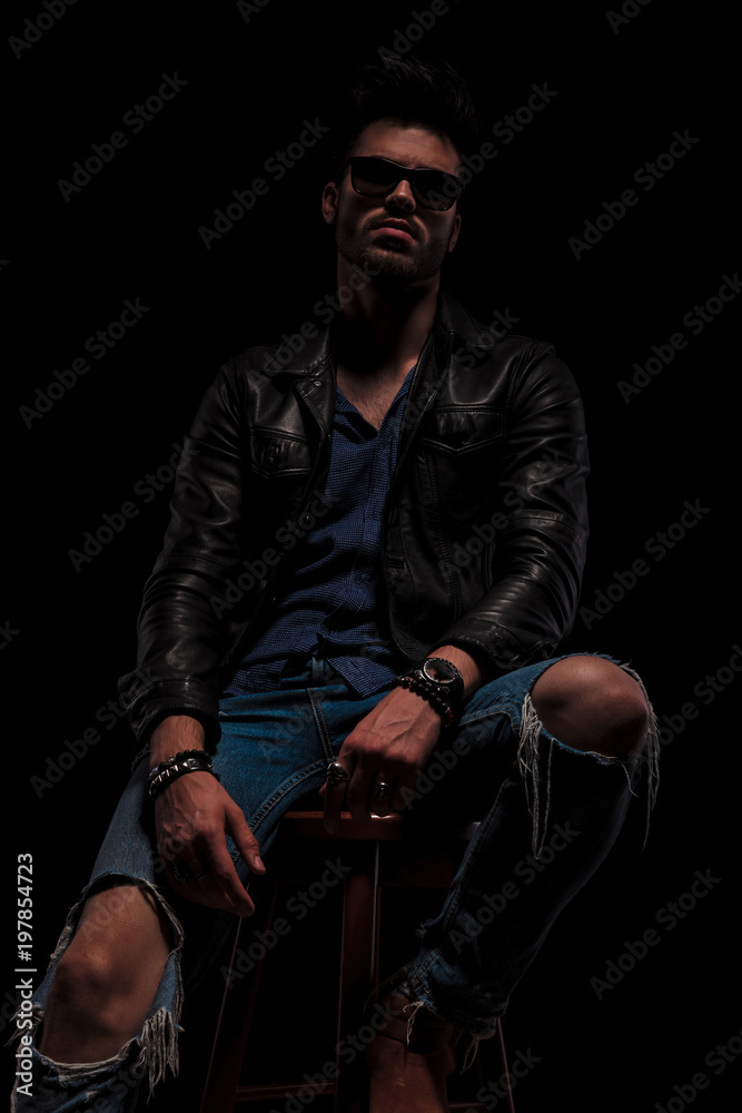 seated fashion man with sunglasses posing seductively