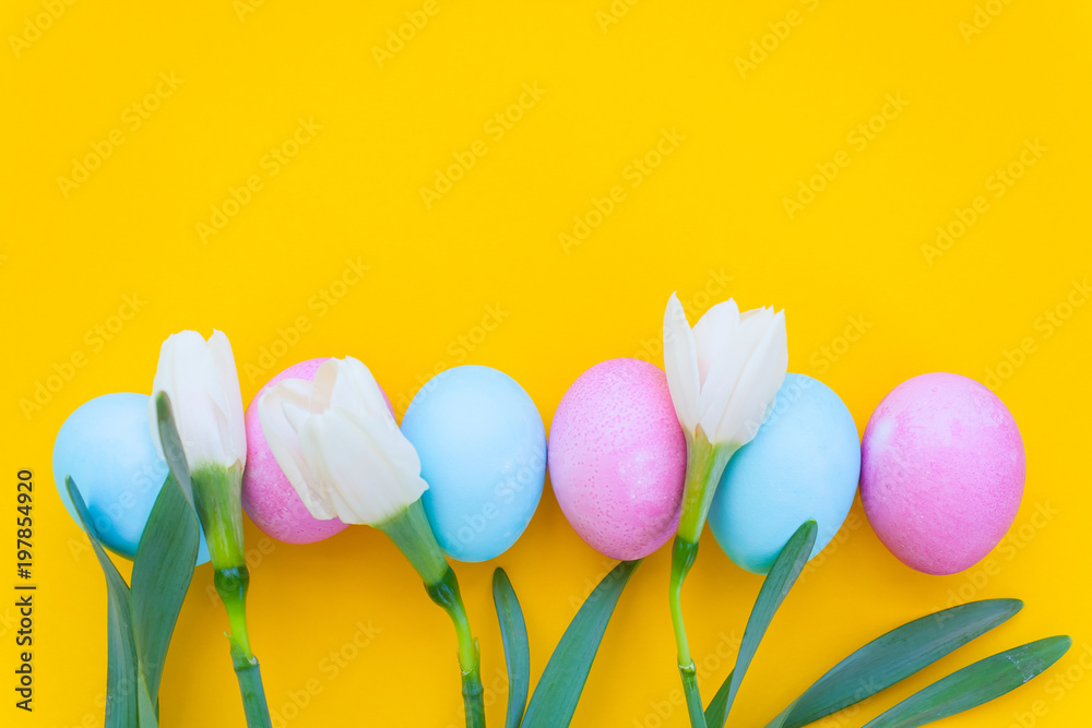 Easter eggs and spring flowers on yellow background