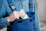 Builder putting money into the pocket of his working uniform