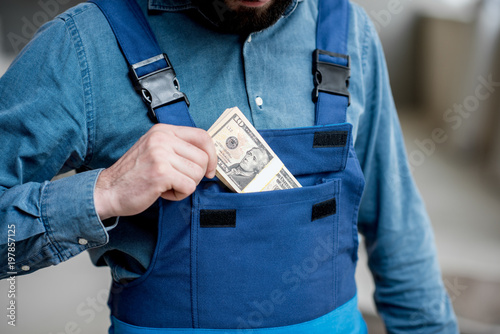 Builder putting money into the pocket of his working uniform
