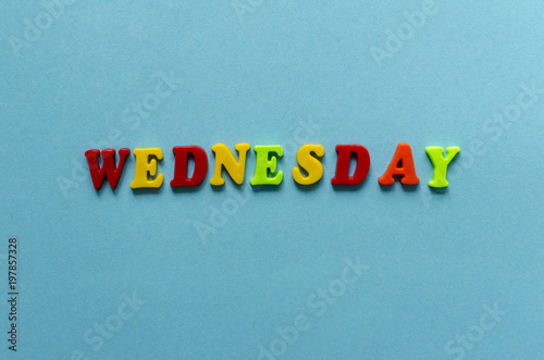 word "wednesday" of colored plastic magnetic letters on blue paper background