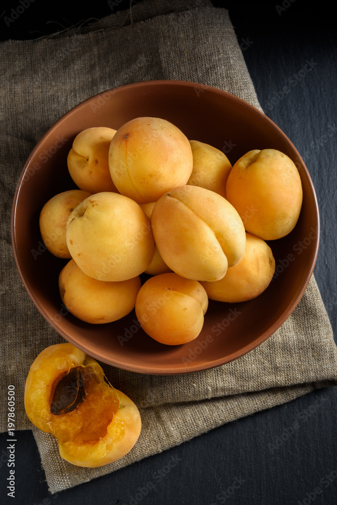 Apricots in bowl on linen and black slate stone Apricots in bowl on linen and black slate stone