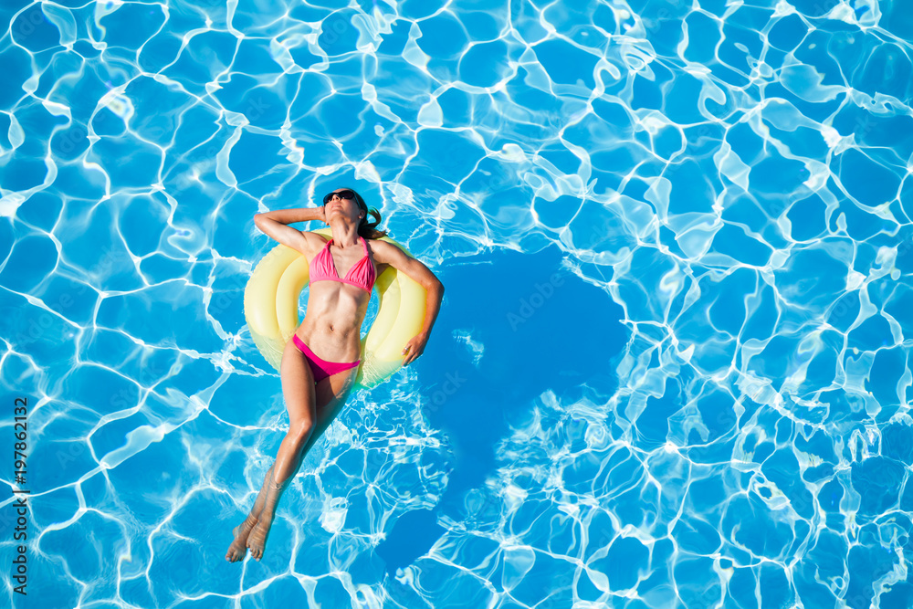 Woman sunbathing on yellow rubber ring in the pool Woman sunbathing on yellow rubber ring in the pool