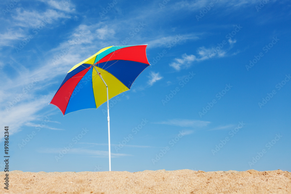 Multicolored beach umbrella against blue sky