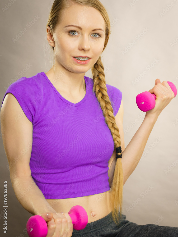 Teenage woman working out at home with dumbbell Teenage woman working out at home with dumbbell