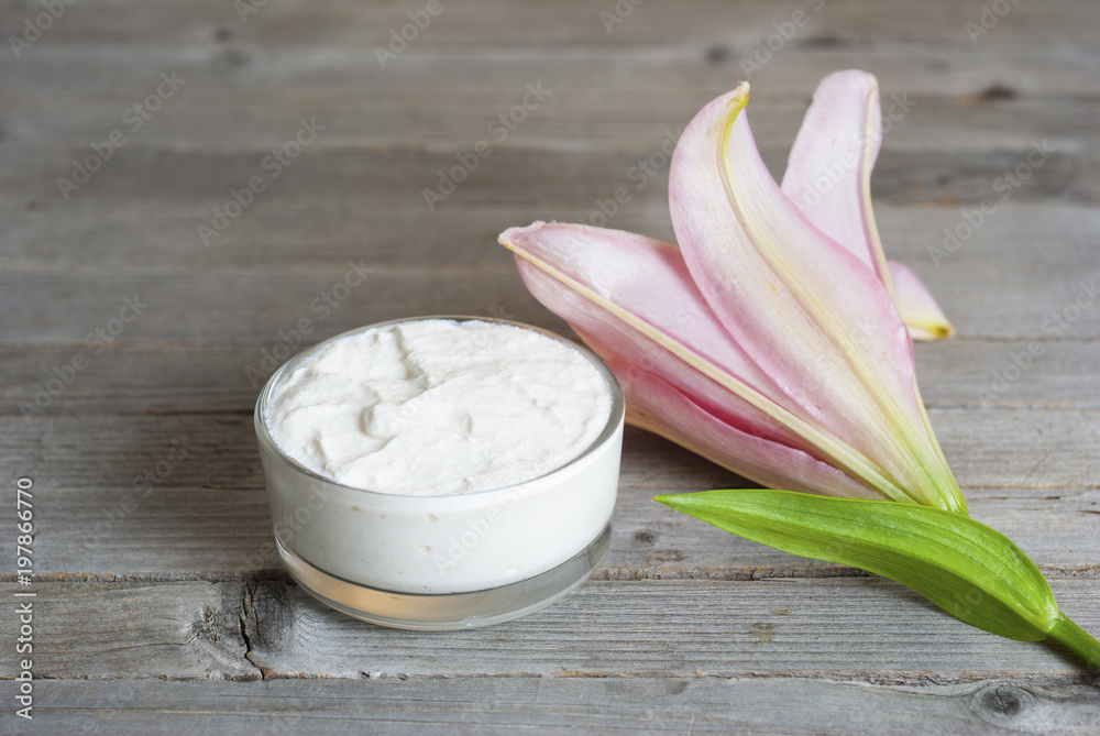 Moisturizer and lily flower on weathered wooden Moisturizer and lily flower on weathered wooden