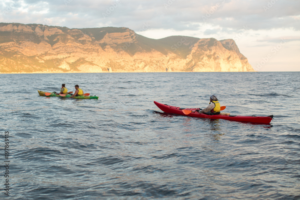 Kayaks. Canoeing in the sea near the island with mountains. People kayaking in the ocean.