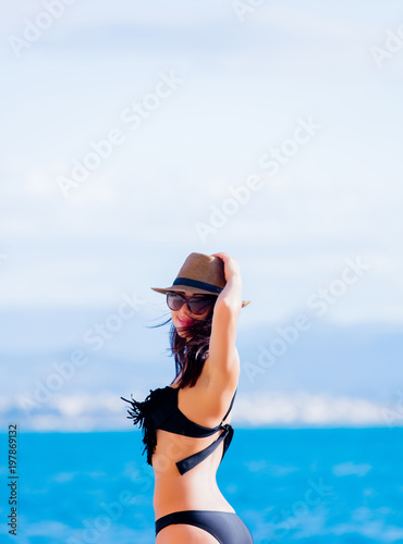 Young beautiful girl in bikini on the beach in Greece. Summertime vacation concept