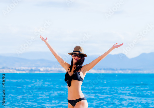 Young beautiful girl in bikini on the beach in Greece. Summertime vacation concept