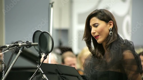 Opera singer sings in the microphone with the orchestra