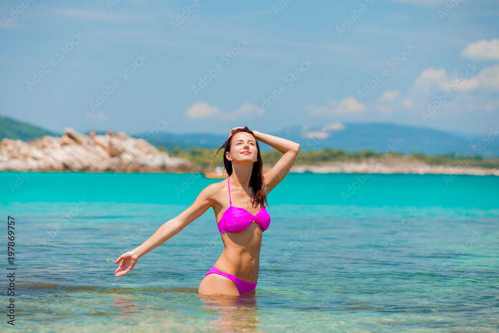 Young beautiful girl in bikini on the beach in Greece. Summertime vacation concept