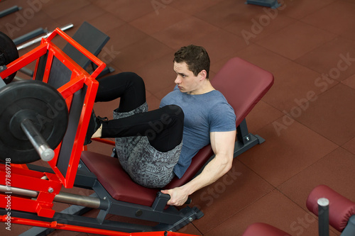 Attractive Young Man Doing Leg Press On Machine In Gym.