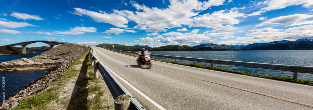 Fototapeta premium Biker rides a road with Atlantic Ocean Road in Norway.