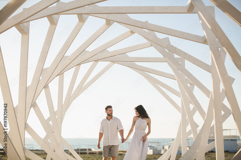 Man and woman posing. Geometric wooden structures. The bride and groom.