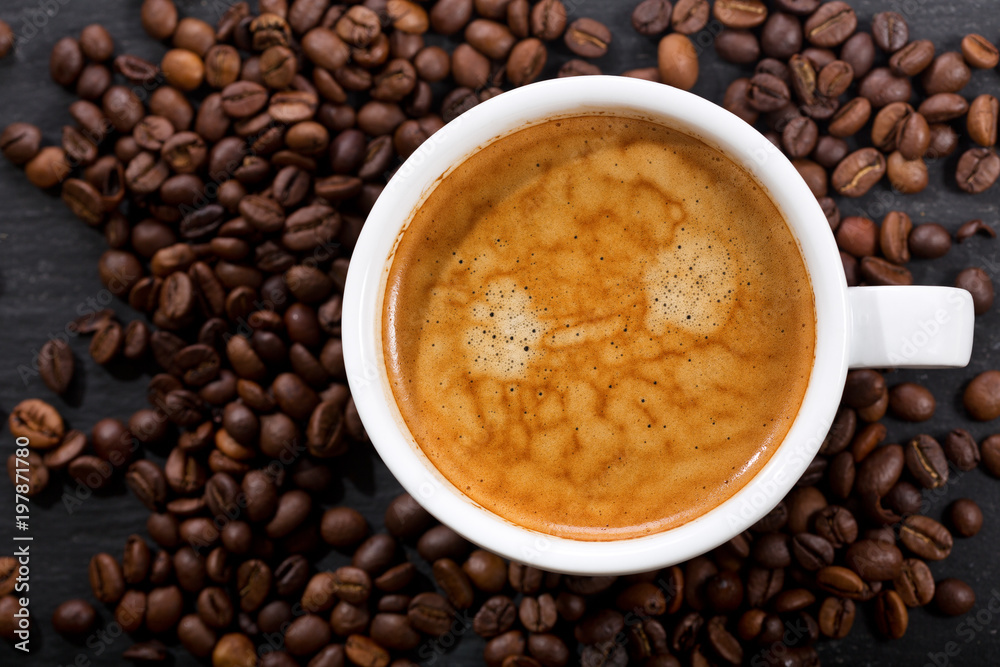 Obraz premium cup of coffee and coffee beans on dark table