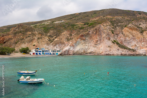 Boats anchoring in beautiful Firopotamos Bay with emerald green sea water, Milos, Cyclades Islands, Greece.