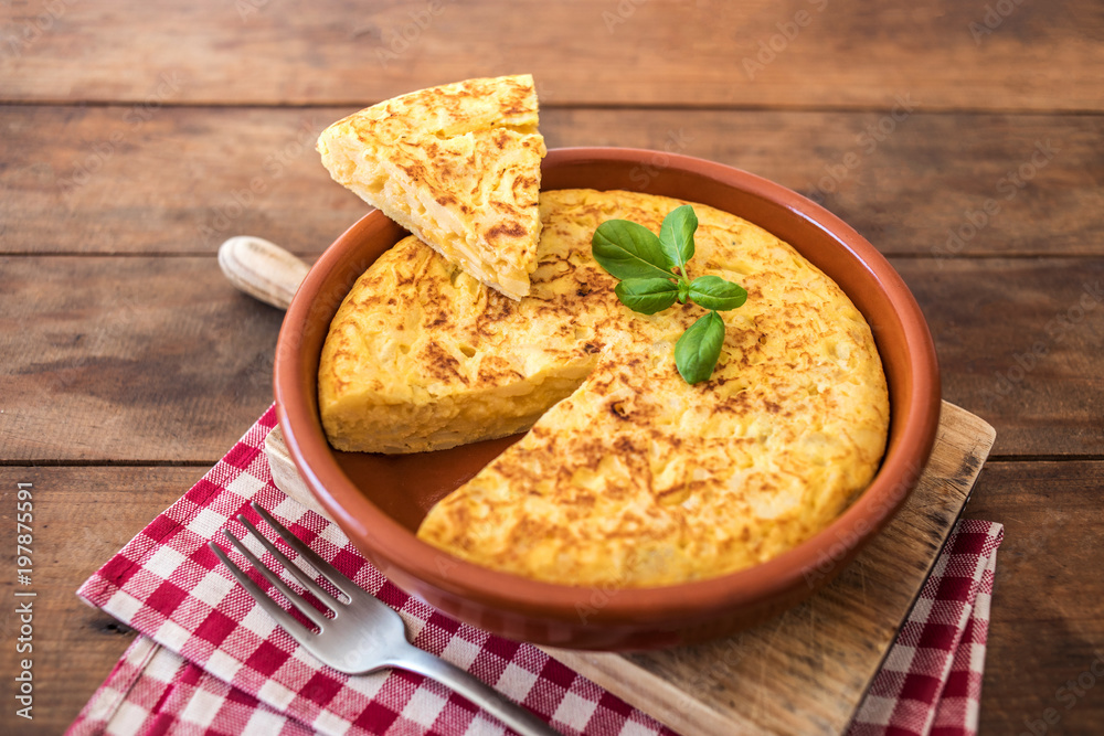 Spanish potato omelet called tortilla de patatas on a rustic wooden texture with a place for text. Spanish potato omelet called tortilla de patatas on a rustic wooden texture with a place for text.
