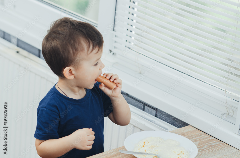 baby eating sausage in the kitchen is very charming and emotional baby eating sausage in the kitchen is very charming and emotional