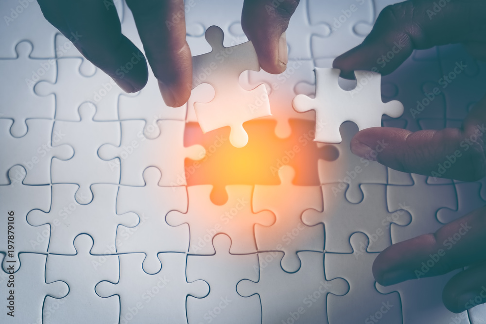 Two hand trying to connect puzzle piece to fill the missing pieces. Jigsaw  puzzle piece with light glow symbol of connection. Business strategy  concept. Soft focus Photos | Adobe Stock