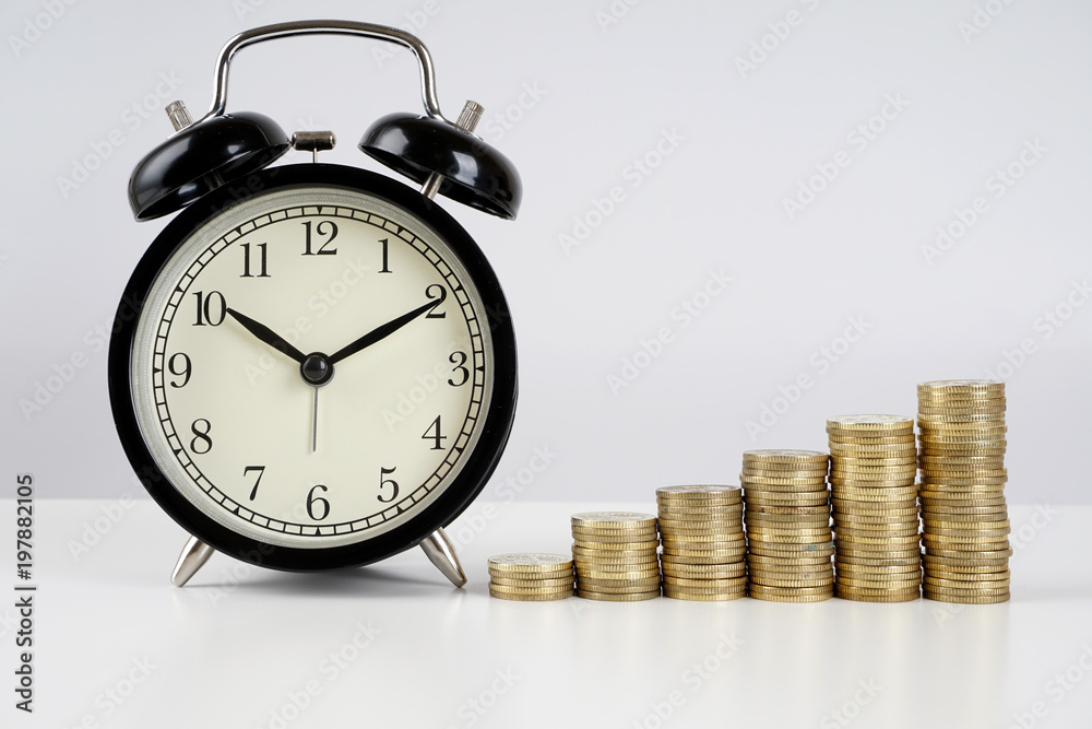 Alarm clock and coins on a white surface Alarm clock and coins on a white surface