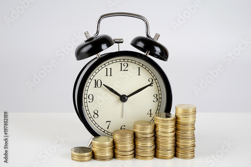 Alarm clock and coins on a white surface